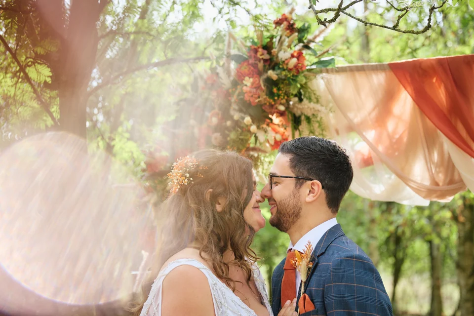 A couple beneath the trees at an outdoor woodland wedding