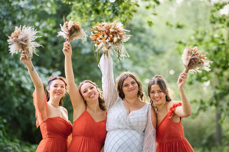 Bridesmaids raising their bouquets together
