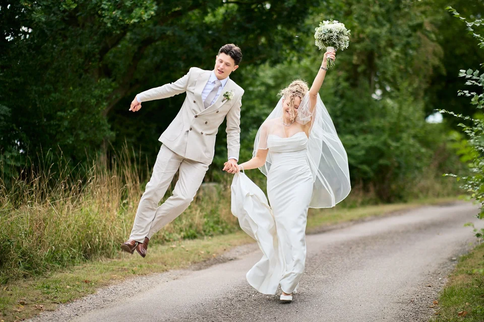 The couple jumping and laughing on a garden path