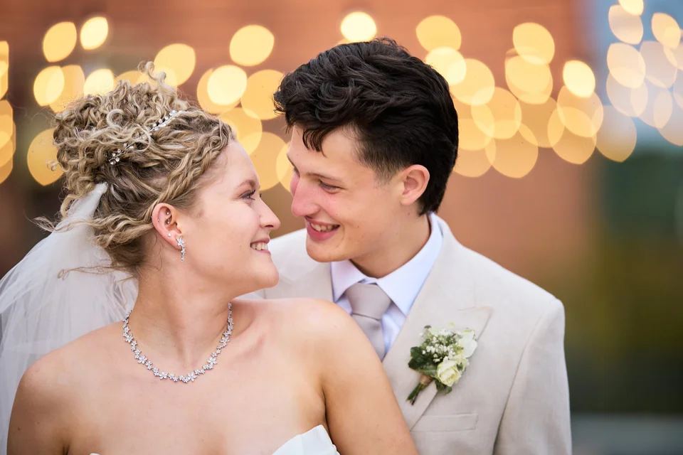 A portrait of the couple beneath strings of lights