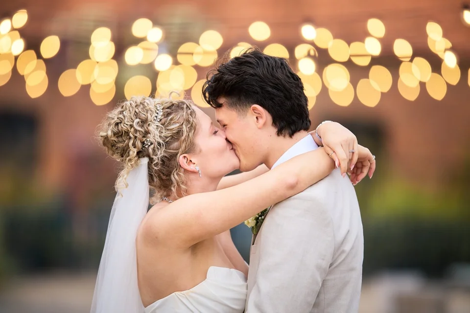 Madi and Brandan kissing beneath strings of fairy lights
