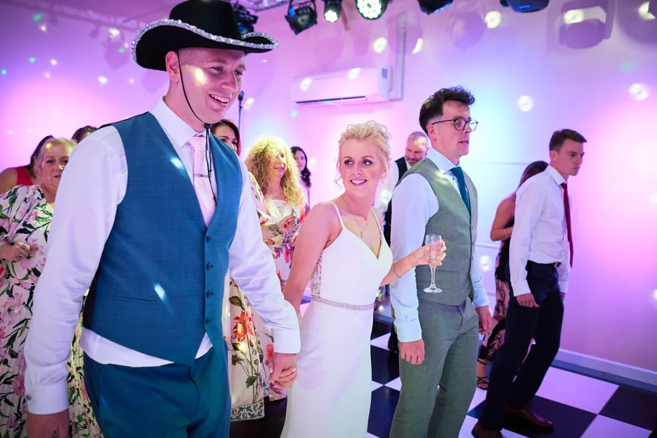 The groom dancing in a cowboy hat