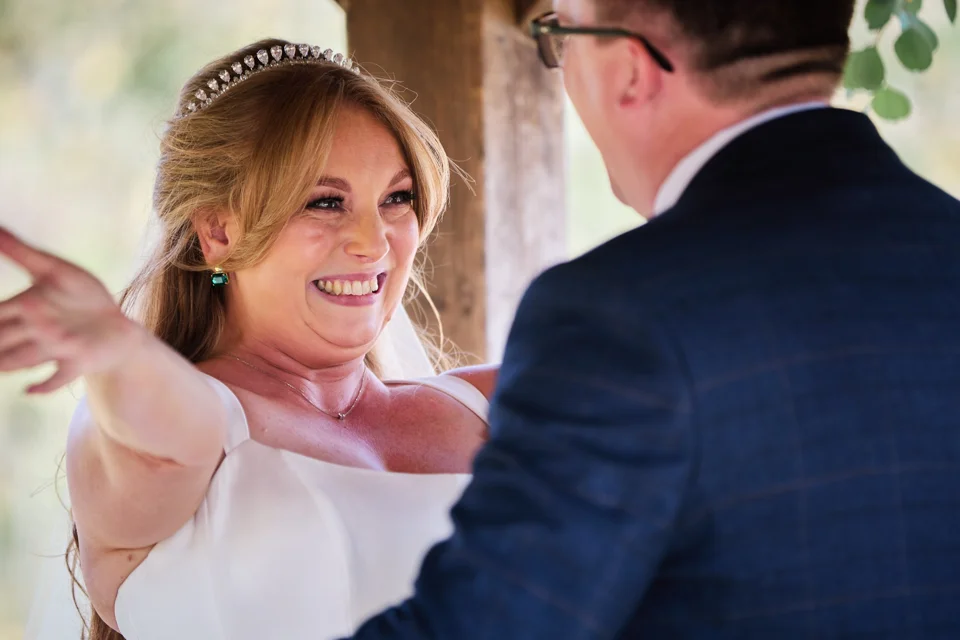 The couple smiling at one another during the ceremony